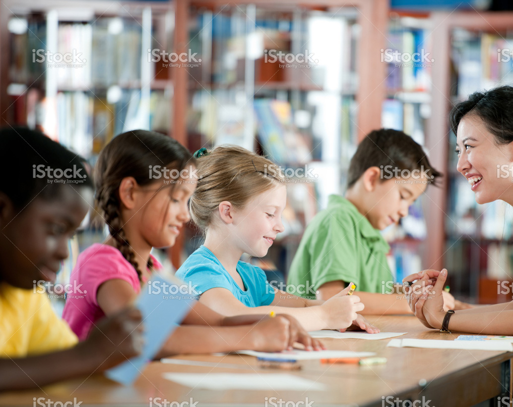 children sitting in desks across from teacher