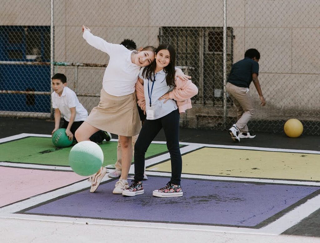 “two students at tuition-free Provident Charter School smiling together on the playground”