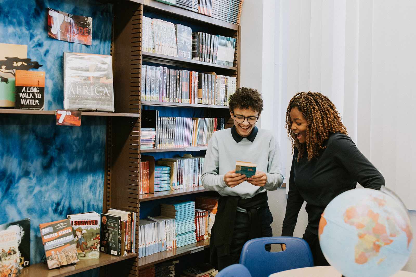 Students at PCS elementary and middle charter school laughing together over a paperback book.